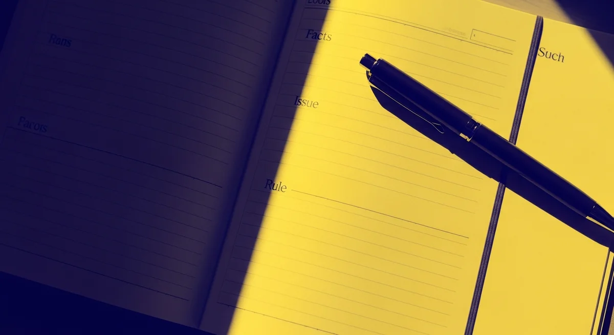 A black pen resting on an open journal with headers for Facts, Issue, and Rule