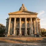 A grand, classical American courthouse exterior, bathed in warm golden hour sunlight, highlighting imposing stone columns